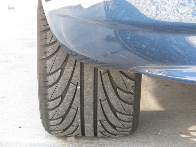 Autoreifen mit fahrendem Auto im Hintergrund