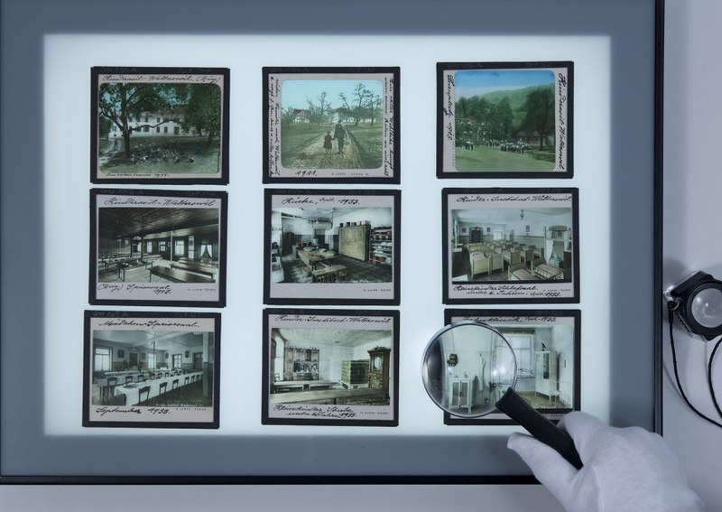 9 Fotoglasplatten auf Diabetrachter, Untersuch der Bilder mit einer Lupe