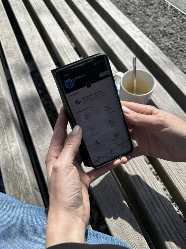 Situationsbild mit Person welche ein Handy in der Hand hält